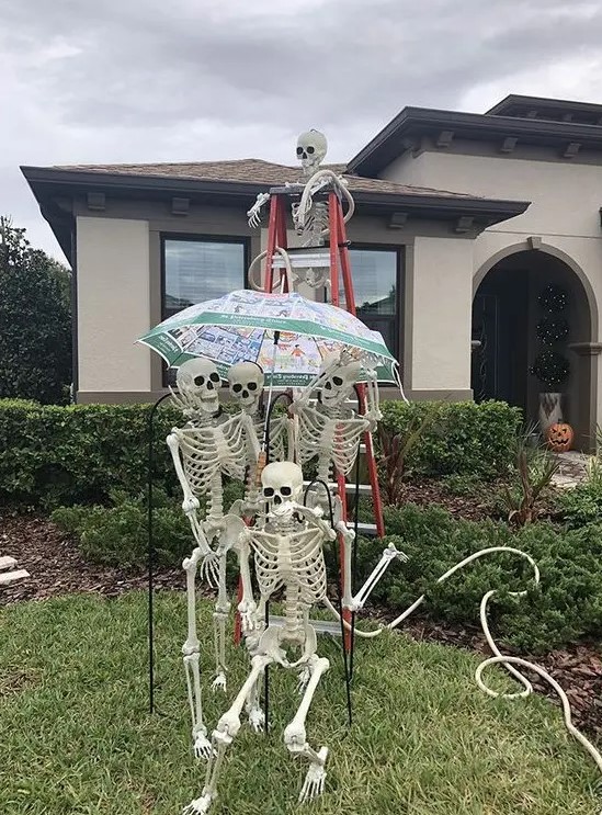 a fun skeleton scene sitting on a ladder and with an umbrella is a cool idea for Halloween outdoor styling
