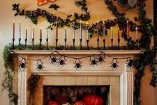 a jaw-dropping Halloween mantel with a moss garland and lots of candles, greenery on the wall, lots of colorful pumpkins and jack-o-lanterns in the fireplace