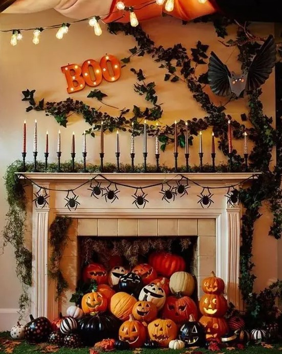 a jaw-dropping Halloween mantel with a moss garland and lots of candles, greenery on the wall, lots of colorful pumpkins and jack-o-lanterns in the fireplace