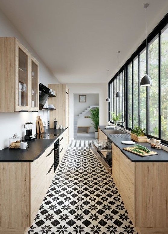 a light stained plywood kitchen with black countertops, a glazed wall, black shelves and pendant lamps