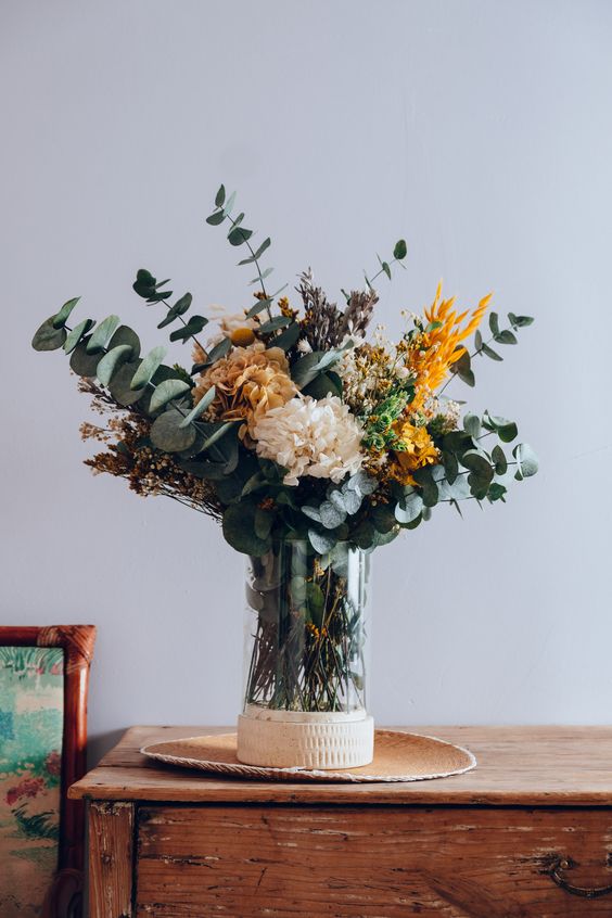 a lovely fall flower arrangement of eucalyptus, dried grasses and some faux flowers is a lovely idea