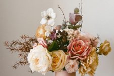 a lovely faux flower arrangement in white, pink, yellow, with dark leaves and twigs, will work for summer or fall