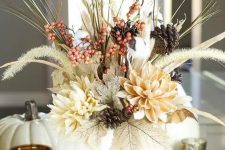 a lovely textural and dimensional Thanksgiving centerpiece of leaves, neutral blooms, berries, twigs and pinecones is wow
