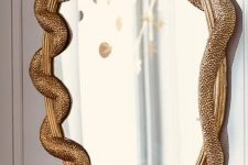 a mirror in a gilded frame with gold snakes is a chic and refined decor idea for Halloween