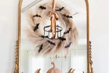 a mirror in a vintage frame, with a pampas grass wreath, a ribbon and black bats is a cool idea for Halloween