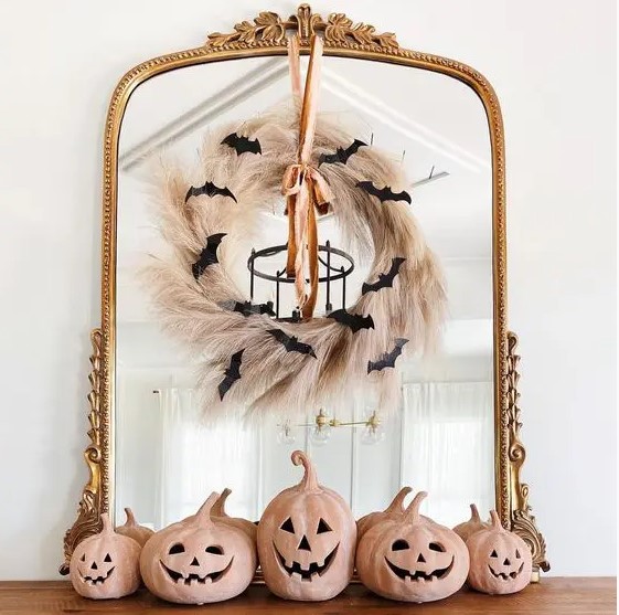 a mirror in a vintage frame, with a pampas grass wreath, a ribbon and black bats is a cool idea for Halloween