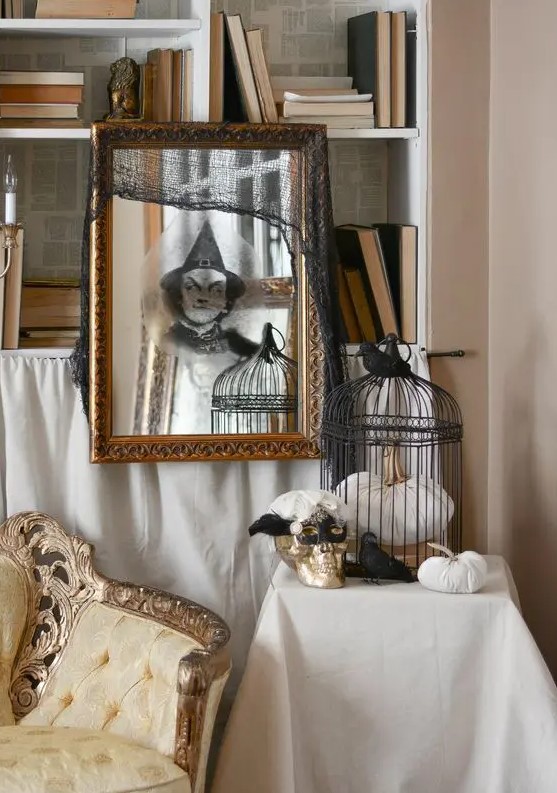 a mirror in a vintage gilded frame with a ghost sticker and a black cheesecloth piece is great for Halloween
