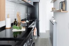 a modern narrow kitchen with grey and stained cabinets, ledges and shelves, a white subway tile backsplash and potted greenery
