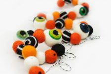a monster eye felt ball garland is a cool decor idea for Halloween, it looks bright and chic