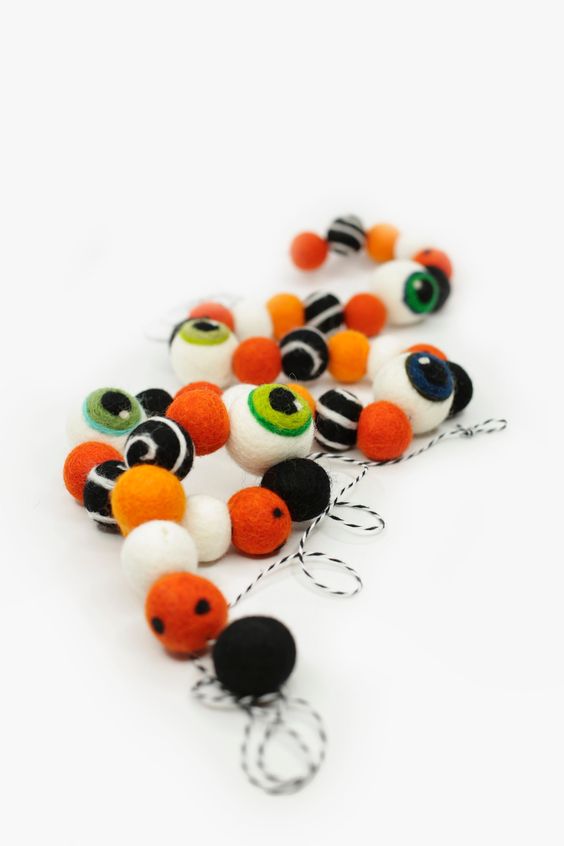 a monster eye felt ball garland is a cool decor idea for Halloween, it looks bright and chic