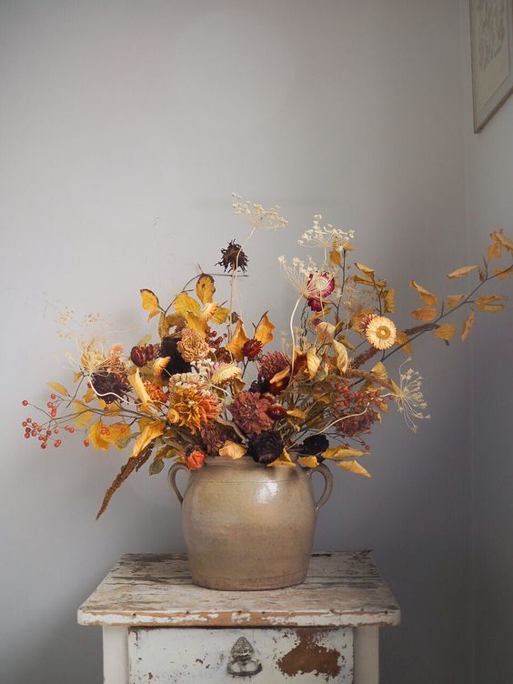 a moody fall dried flower arrangement with various blooms, leaves and grasses is a stylish idea for fall or Halloween