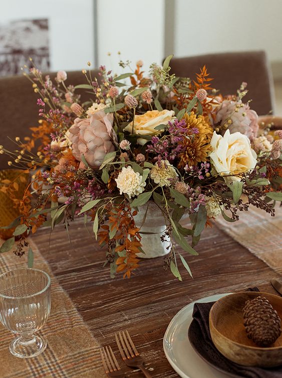 a moody faux flower arrangement in neutrals, yellow, mauve, mustard, with greenery and bold leaves for the fall