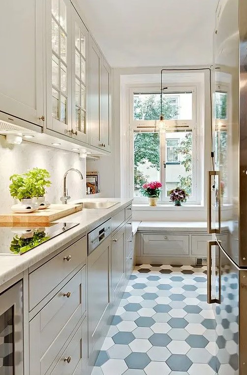 a narrow kitchen with shaker cabinets, built in lights, a tile floor, a windowsill daybed and some herbs and blooms