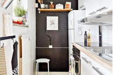 a narrow kitchen with sleke white cabinets, butcherblock countertops, a chalkboard wall, printed textiles and herbs in planters