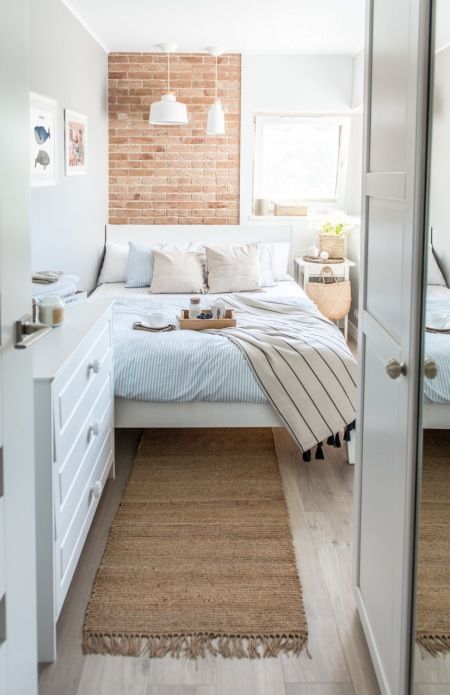 a narrow light-filled bedroom with a dresser, a bed with neutral bedding, pendant lamps and a nightstand with some decor