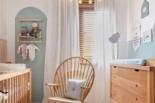 a neutral and pastel nursery with stained furniture, an accent wall, a makeshift closet and lights and lamps is very welcoming