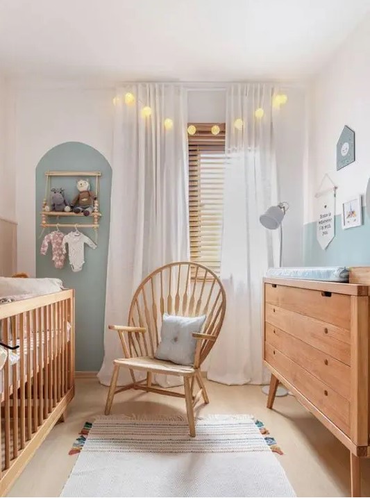 a neutral and pastel nursery with stained furniture, an accent wall, a makeshift closet and lights and lamps is very welcoming
