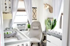 a neutral modern nursery with a grey and white crib, a matching dresser, a grey chair, light grey curtains and some decor