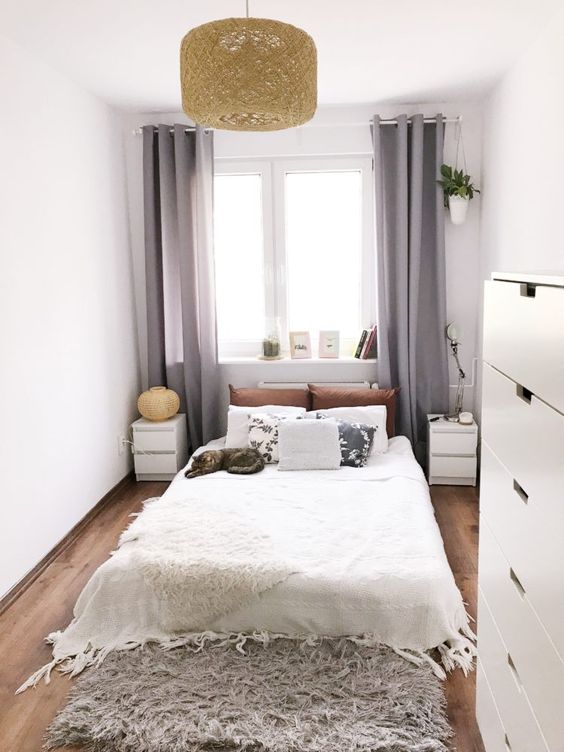 a neutral narrow bedroom with a bed, matchign nightstands, a fluffy rug, a pendant lamp and a dresser