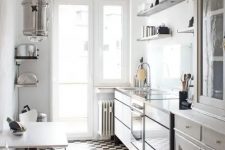 a neutral narrow kitchen with vintage cabinets and open shelving, a checked floor, a table and white chairs and pendant lamps