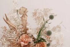 a pretty dried and fresh flower centerpiece with lunaria, dried and white spray painted leaves, with allium, rust and peachy roses is cool