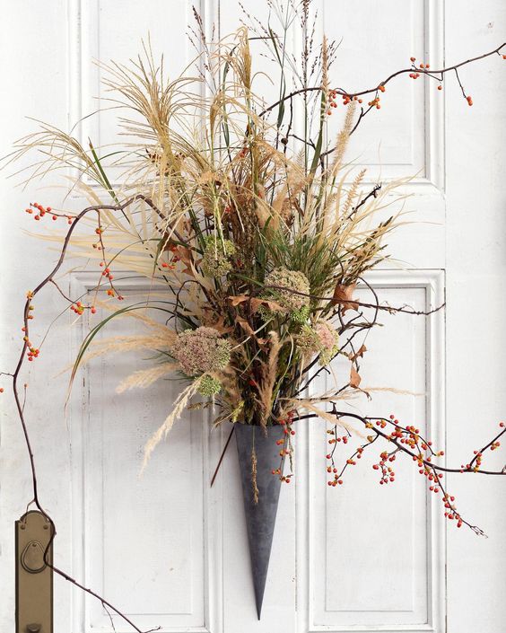 a pretty fall door decoration of a cone, with twigs and berries, dried grasses is a cool alternative to a usual wreath
