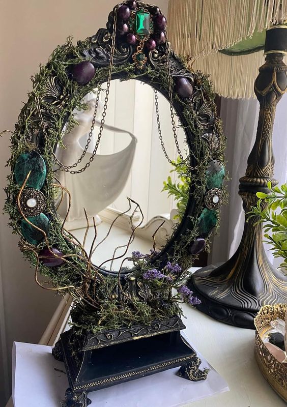 a refined vintage Halloween mirror decorated with large purple and emerald gemstones, twigs and chain is amazing