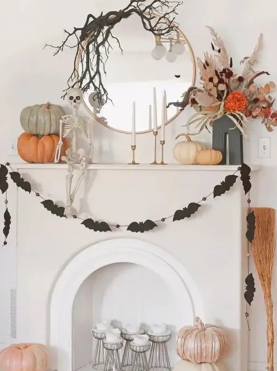 a round mirror with black branches on top, a black bat garland, stacked pumpkins, a dried flower arrangement and a skeleton