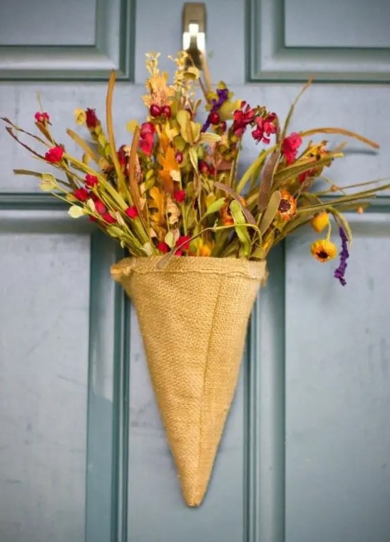 a rustic door arrangement of a burlap cone, faux blooms and greenery is a nice alternative to a usual door wreath
