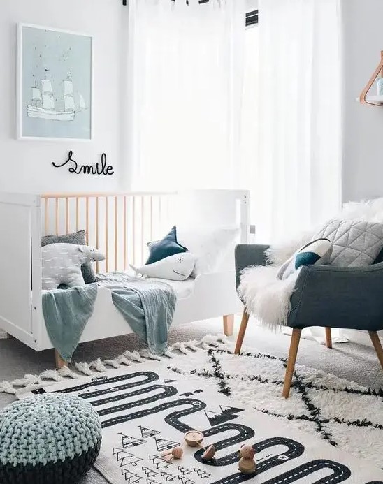 a small Scandinavian nursery with a white crib, a grey chair, pastel pillows and textiles, some artwork and layered rugs plus poufs