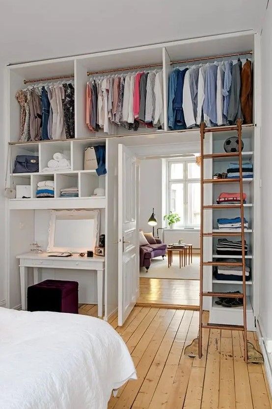 a small bedroom with railing and open storage shelves over the doorway that comprise a closet to save floor space