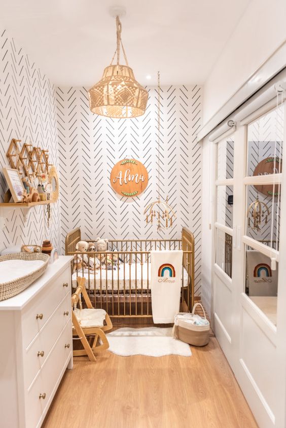 a small boho nursery with accent walls, a metal crib, a white dresser, bookshelves, some furniture and lvoely boho decor