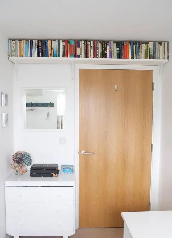 a small bookshelf over the doorway allows to store a lot of books and not to clutter the small space at the same time