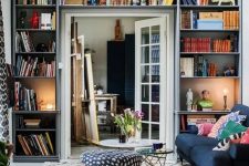 a small living room with open shelves taking a whole wall with the door – a smart idea that allows to store a lot of things here