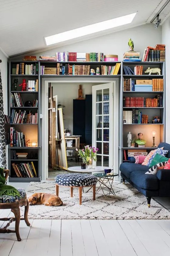 A small living room with open shelves taking a whole wall with the door   a smart idea that allows to store a lot of things here