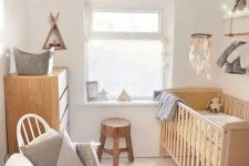 a small organic nursery with stained and white furniture, neutral bedding and textiles, a makeshift closet, a pendant lamp and lights