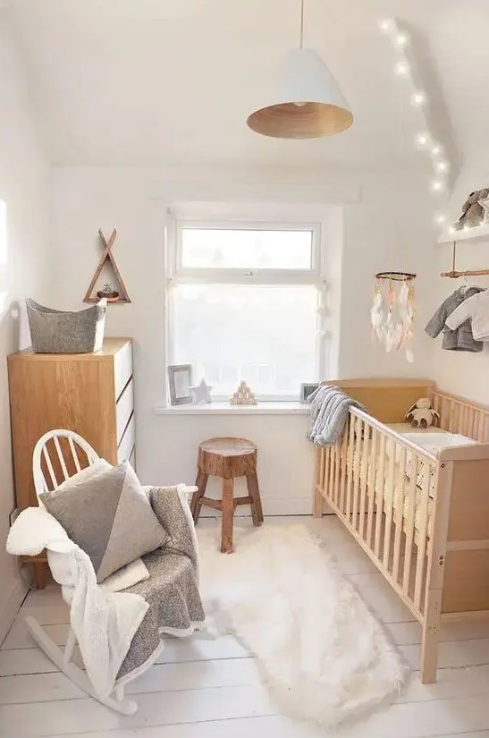 a small organic nursery with stained and white furniture, neutral bedding and textiles, a makeshift closet, a pendant lamp and lights