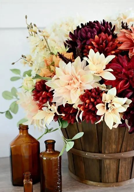 a stylish fall arrangement of blush, white and burgundy faux blooms in a basket is a cool rustic piece to rock