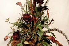 a stylish fall centerpiece of a vintage urn, greenery, feathers and faux blooms is an elegant boho-inspired decoration to make for fall