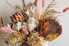a stylish fall flower arrangement of hydrangeas, pink and neutral grasses, leaves and other stuff including berries