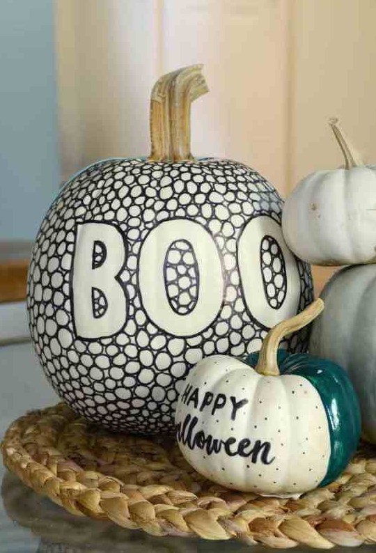 a super cool black and white pumpkin made with a sharpie and a green, black and white one made using a sharpie and some paint