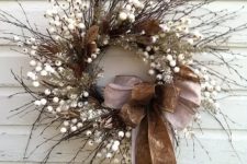 a textural twig wreath with faux berries, brown leaves, two large bows and silver branches for fall to winter period
