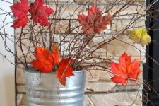 a tin bucket with twigs and branches and with bright fall leaves is a gorgeous and very easy fall decoration