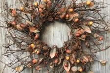 a twig fall wreath with acorns, berries, faux leaves and pinecones looks and feels very fall-like
