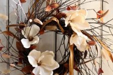 a twig fall wreath with dried fall leaves, bunny tails, white blooms and a striped ribbon is a lovely fall decoration
