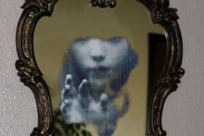 a vintage mirror in a chic frame with a ghost detail is a super eye-catchy and stylish idea for Halloween