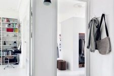 a white Scandinavian entryway with an open shelf over the doorways to store shoes and boots that aren’t worn right now