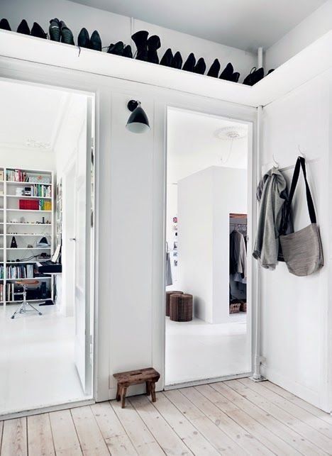 a white Scandinavian entryway with an open shelf over the doorways to store shoes and boots that aren't worn right now