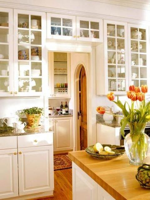 a white modern farmhouse kitchen with shaker cabinets, glass cabinets including those placed over the door to get even more space
