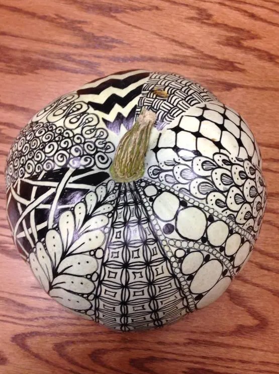 a white pumpkin decorated with a black sharpie in various ways is a lovely idea for modern Halloween parties